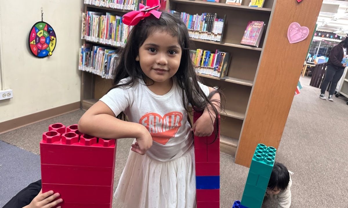 A young girl playing with colorful Duplo blocks at the Chicago Public Library, enjoying a creative and educational activity in the children's section surrounded by books.