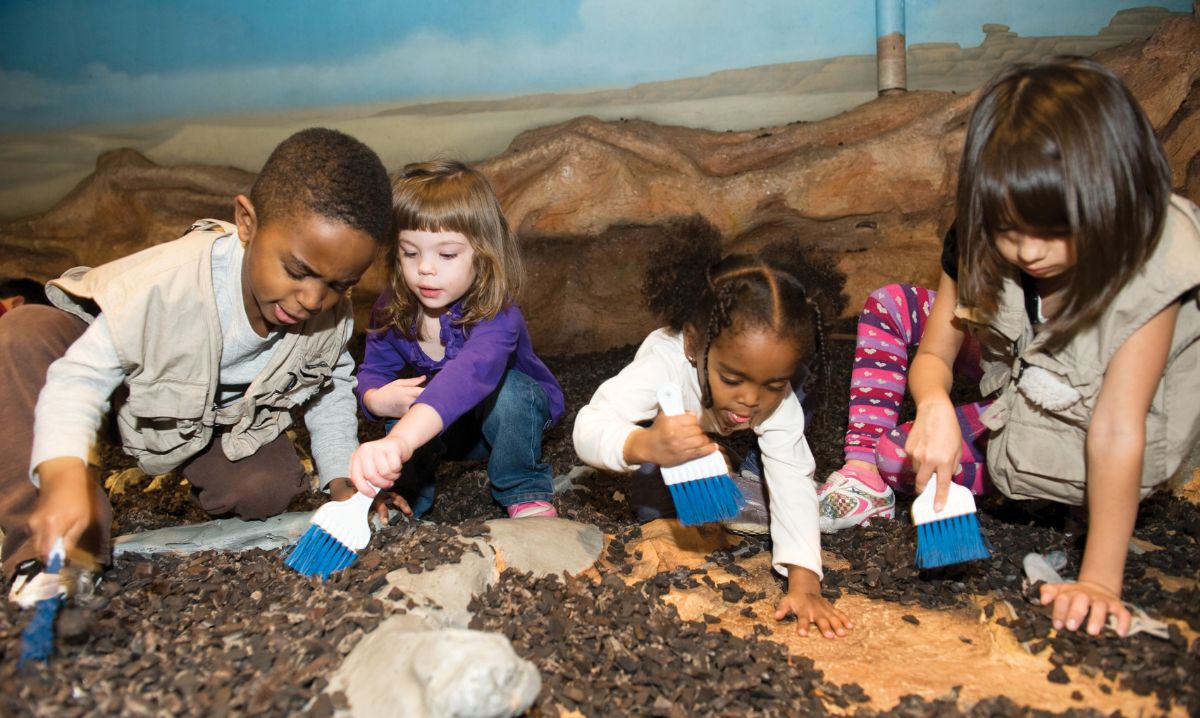 Young children participating in a hands-on dinosaur excavation activity at Chicago Children's Museum, a popular destination for indoor animal experiences in Chicago.