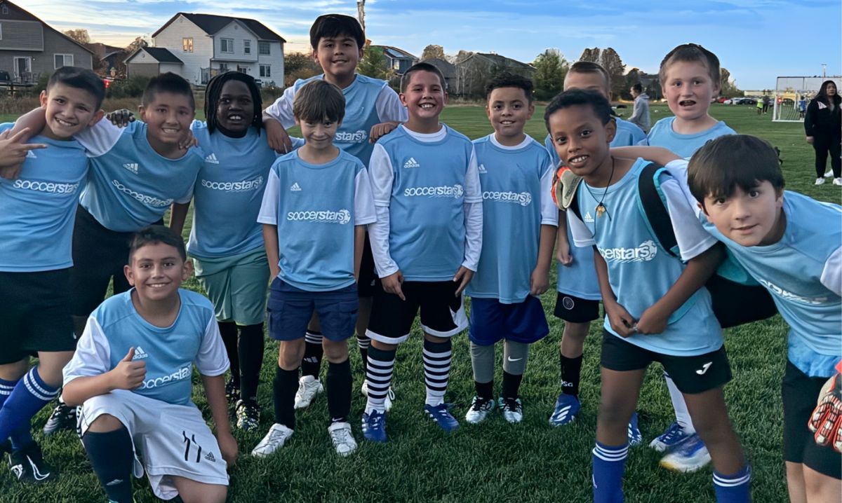 A group of young athletes at Soccer Stars Camps posing together on the field, building teamwork and skills.