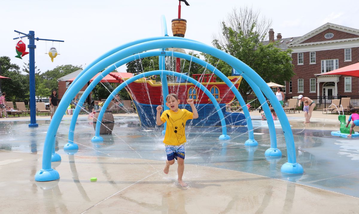 Child running through water arches at Prospect Park Splash Pad in Park Ridge, a fun family-friendly destination near Chicago for splash pad play.